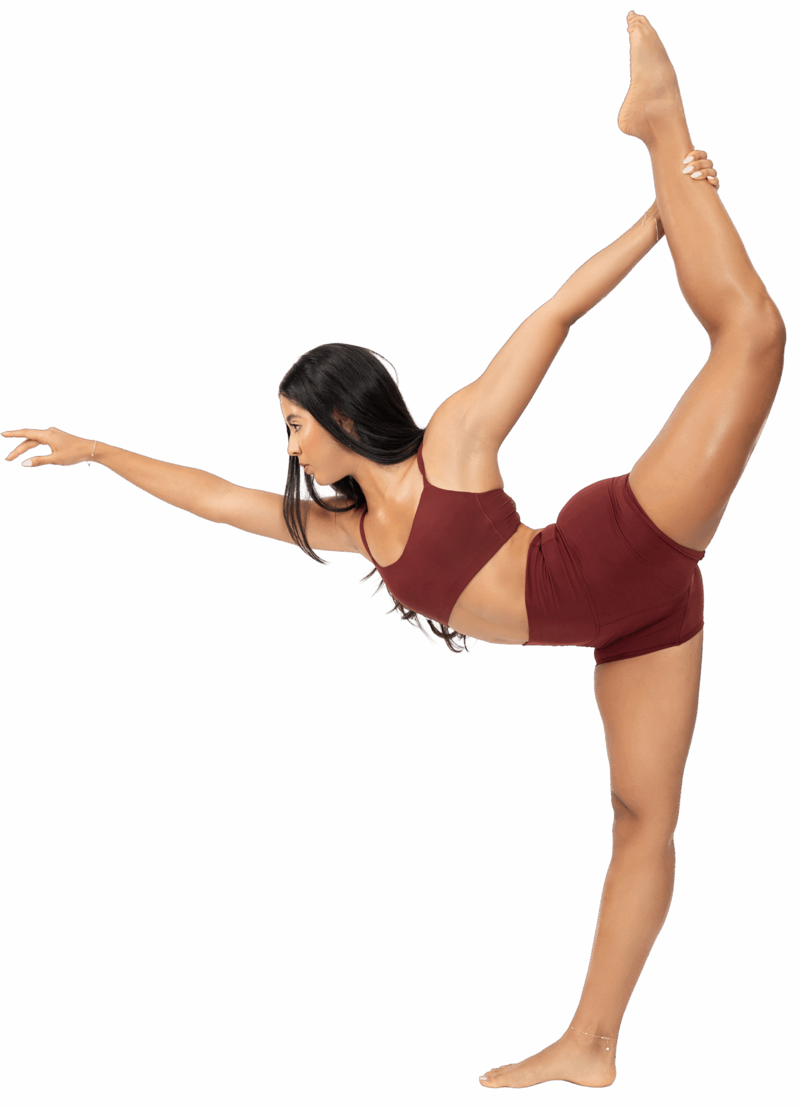 A woman in a maroon outfit performs a yoga pose against a bright red background.